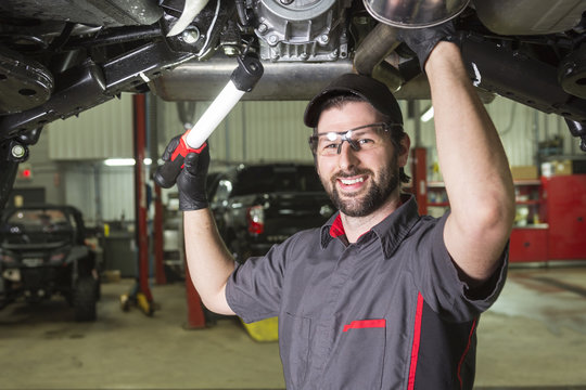 Mechanic working on car in his shop - Powered by Adobe