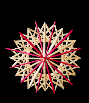 Straw star Christmas decoration on black background. Handmade colorful decor for windows, as gifts or to hang on the xmas tree, traditionally made from natural straw. Macro photo front view close up.