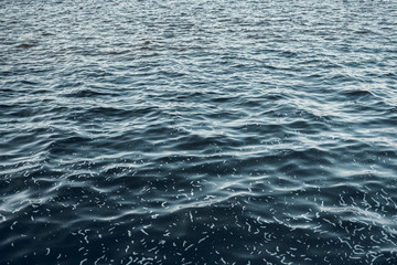 Sea surface aerial view. Background shot of clear sea water surface. Blue sea water in calm. Sea texture. Background blue waves of the sea with sea foam.