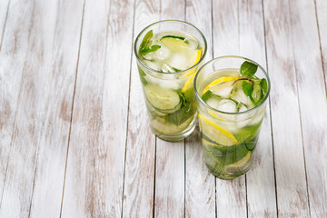 Water with lemon, mint and cucumber on wooden light background. Water Detox.
