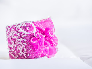 Fototapeta na wymiar Pink gift box on gentle fabrics background