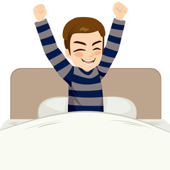 Young man happy waking up sitting on bed with arms up