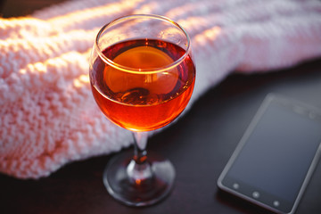 Red wine and mobile phone with white blanket.Sunny evening.Toned bokeh image.