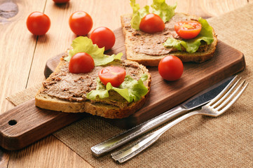 Chicken liver pate on the bread on wooden tray.