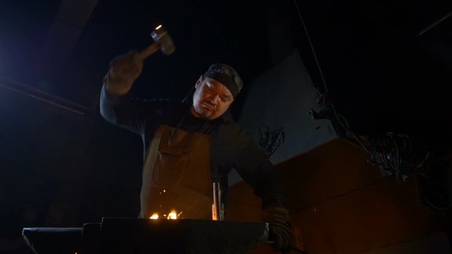 Blacksmith hammer strikes. Slow motion