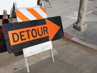 Orange on black detour arrow at street repair. Horizontal.