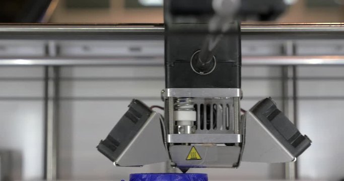 Front close-up view of 3d printer in process It makes pieces for equipment with blue plastic