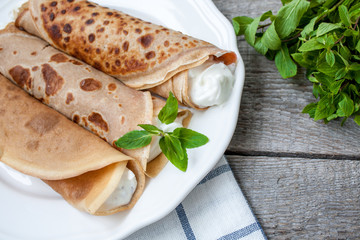 Russian thin pancakes with butter, cheese, jam, mint on a napkin on a wooden background.  Love for a healthy sweet  food concept