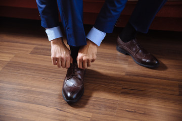 Business man dressing up with classic, elegant shoes. Groom wearing on wedding day, tying the laces and preparing.