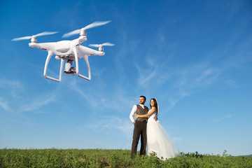 Hovering drone taking pictures of wedding couple in nature - Powered by Adobe