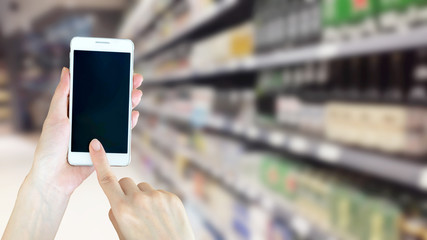 Woman using smart phon while shopping in supermarket