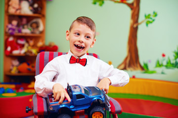 cute happy kid on wheelchair with present in kindergarten for kids with special needs