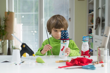 Little boy being creative making homemade do-it-yourself toys out of yogurt bottle and paper....