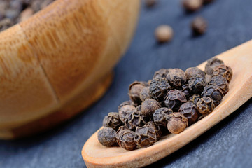 Black peppercorns in a spoon and bowl