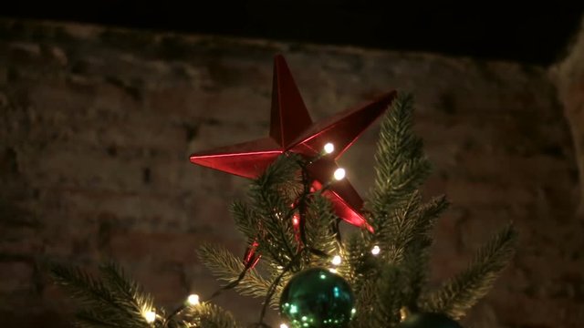 big red star on top Christmas green tree on a background of brick wall