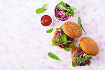 Big sandwich - hamburger burger with beef, pickles, tomato and red onions on a light background. Top view