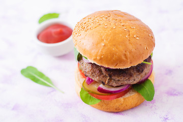 Big sandwich - hamburger burger with beef, pickles, tomato and red onions on a light background.