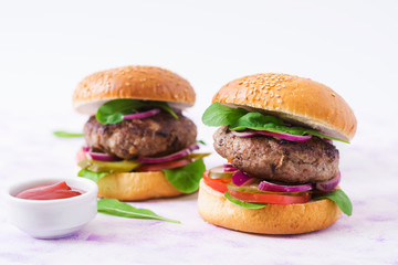Big sandwich - hamburger burger with beef, pickles, tomato and red onions on a light background.