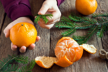 Tangerine and fir branches in children hands