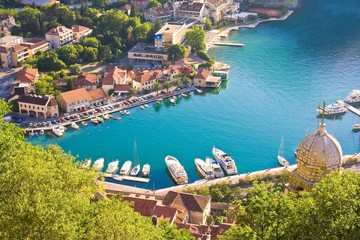 Bay of Kotor in Montenegro with view of mountains, boats and old houses with red tile roofs
