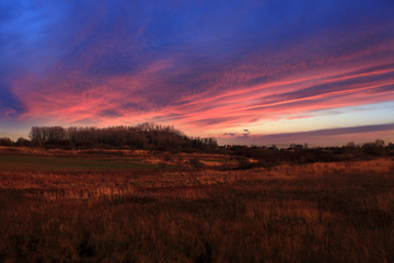 Fototapeta na wymiar Kolorowy zachód słońca nad polami, wioską.