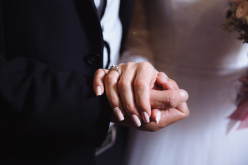 Bride and groom's hands with wedding rings on brown table