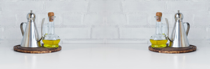 Oil, vinegar, dressing in steel jug and glass jug against kitchen white brick wall. Cooking concept. Wide panoramic.