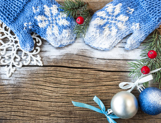 mittens and Christmas decorations on a wooden background