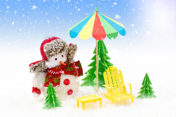 Christmas background, Snowman with sun lounger and beach umbrella.