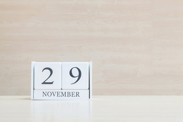 Closeup surface white wooden calendar with black 29 november word on blurred brown wood desk and wood wall textured background with copy space , selective focus at the calendar