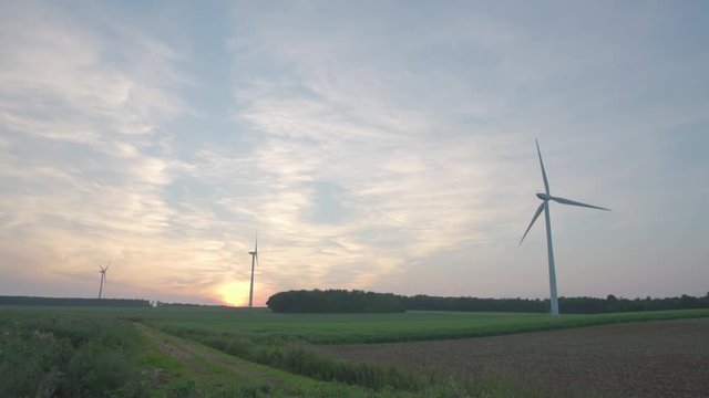 Wind turbines turning at sunset over a field in France