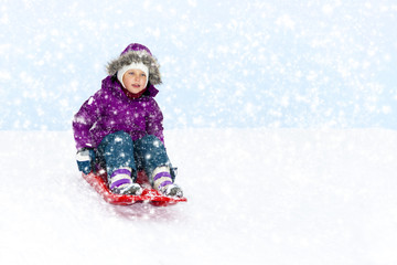 Fototapeta na wymiar Little girl sliding in the snow.