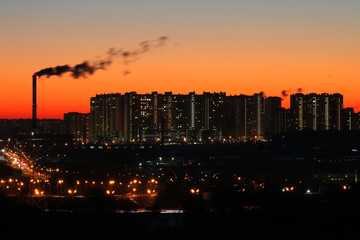 Fototapeta na wymiar Panorama of a large industrial city and high-rise buildings on the background of bright orange sunset sky.