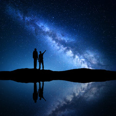 Milky Way with silhouette of a family. Father and a son who pointing finger in night starry sky on...