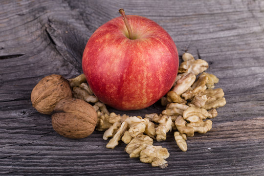 Apple and walnuts on wooden background