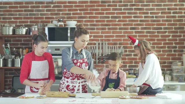 The general plan: a happy family is cooking in the kitchen. Mom manages the process of preparing Christmas cookies and gives the job. Daughter kneads dough. Children and cooking. Mother with children
