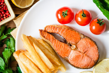 Fried salmon steak with vegetables on plate