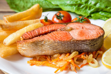 Fried salmon steak with vegetables on plate