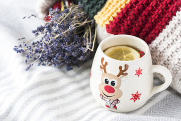 white cup with warming tea and lemon on wooled shawl with knitted scarf  during cold winter day 