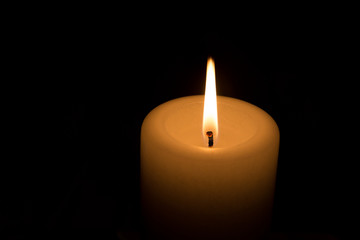 gelbe Kerze brennt im Dunkeln