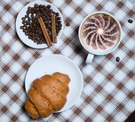 cup of cappuccino with croissant on the table top view