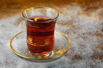 Cup of Turkish tea on saucer in winter on a snowy wooden board