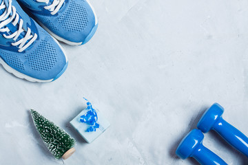 Christmas sport composition with shoes, dumbbells and blue gift
