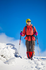 Girl with backpack walking on snow in the mountains.
