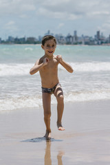 Six year old boy having fun on tropical beach in sunny day