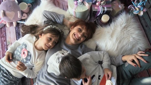 Happy mother having fun with her kids lying on the floor in christmas time