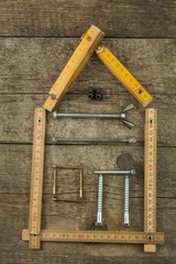 Plans to build a house. Rustic wooden background. Tools for builders. Architect designing a house for a young family. House from nails and screws. Needed for building. Ideas about building a house.
