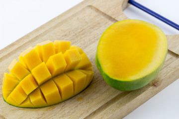 Ripe yellow mango slices on a wood isolate background / mango slice on a cutting board wood white background.