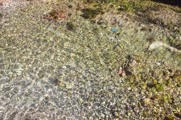 clear waters of the sea lake texture background / Beach pebbles under clear water with waves.