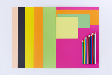Colored paper and colored pencils on white background.